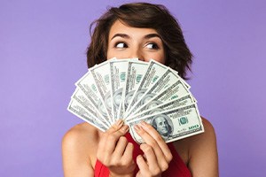 Woman fanning out dollars to hide her smile