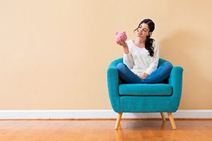 Woman sitting on chair holding her piggy bank