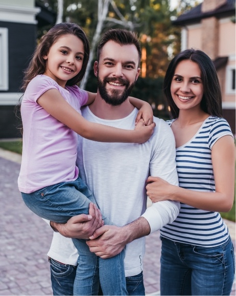 Family of three smiling in their yard