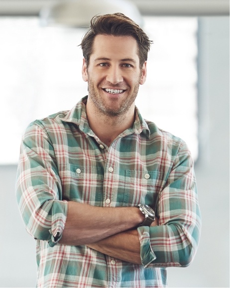 Smiling man with arms crossed in red and green plaid shirt