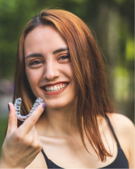 Young woman holding Invisalign tray outdoors