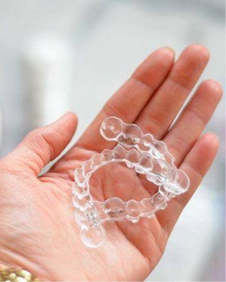 Hand holding two Invisalign aligners