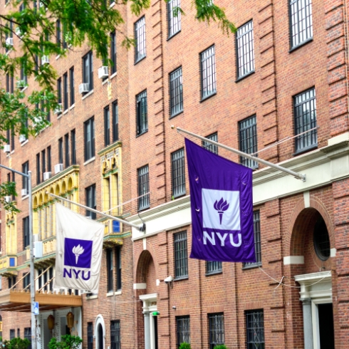 Side of red brick building with New York University flags