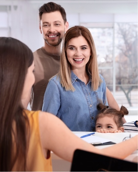 Family of three talking to receptionist at orthodontic office