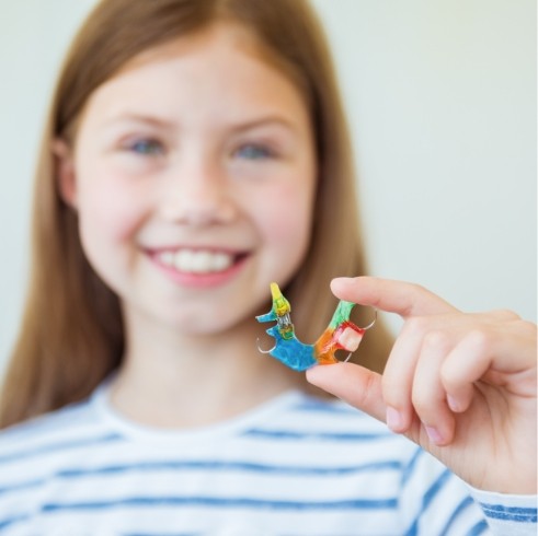 Smiling girl holding a removable retainer