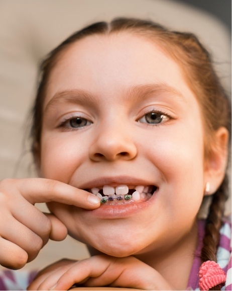 Young girl pointing to braces on her lower teeth